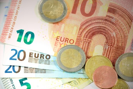 Eine Frau trägt eine Kiste mit Kleidung und Spielzeug zu einer Sammelstelle für Spenden. Sie lächelt in die Kamera.