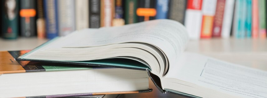 Mehrere Bücher liegen übereinander, eins ist aufgeschlagen.