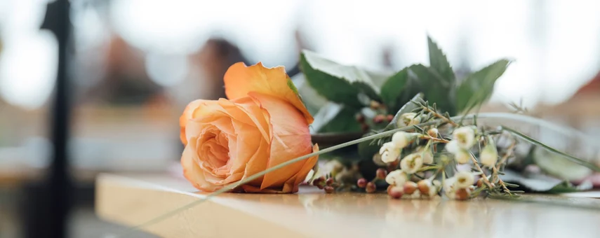 Eine orange Rose liegt auf einem Tisch.