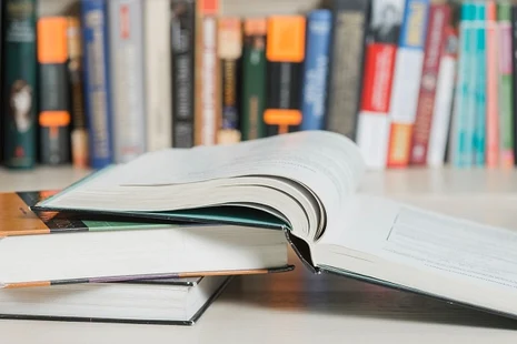 Mehrere Bücher liegen übereinander, eins ist aufgeschlagen.