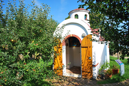 Blick auf Apfelbäume und Byzantinische Basilika mit geöffnetem Tor im Bibelgarten Oberlichtenau