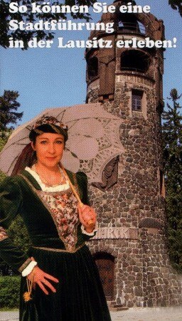Bild einer Frau mit historischem Kleid und elegantem Schirm vor einem Turm