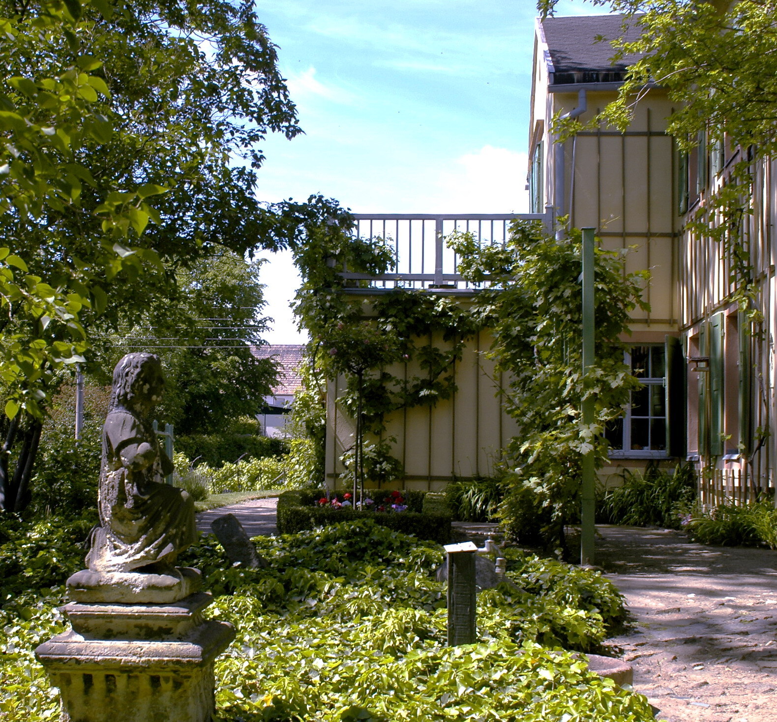 Blick durch den Garten auf das Göschenhaus mit Skulptur im Vordergrund